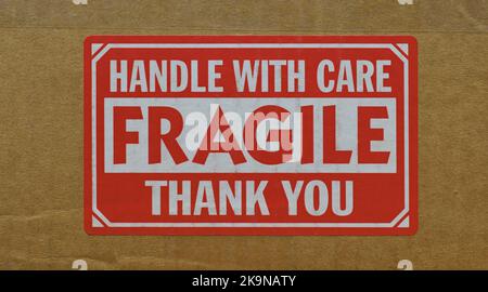 Handle with care sticker attached to the side of a cardboard box. Closeup isolated front view and centered image. Stock Photo