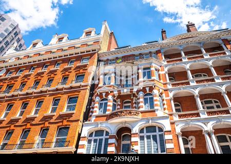 Looking up low angle view on apartment flats house building in Gothic revival style architecture in city of Westminster, London UK with blue sunny sky Stock Photo