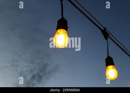 burning light bulbs on the background of the evening sky Stock Photo