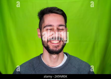 Young man with casual clothes, expressing emotions, posing on green background Stock Photo