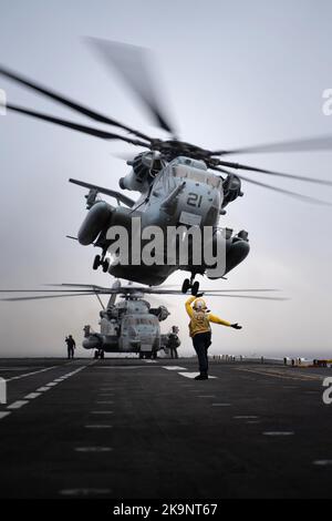 Aviation Boatswain's Mate (Handling) Airman directs a Marine Corps CH-53 Super Stallion helicopter attached to the 22nd Marine Expeditionary Unit (MEU) during flight operations aboard the Wasp-class amphibious assault ship USS Kearsarge (LHD 3) Stock Photo