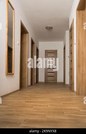 Narrow Corridor with a ceramic floor and doors in apartment Stock Photo