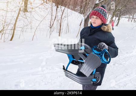 A boy in a city park in winter sledding. Happy childhood and active lifestyle Stock Photo