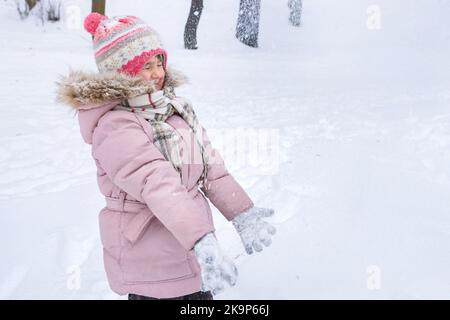 Happy little girl is playing in the winter park. The winter vacation Stock Photo