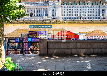 London, United Kingdom - June 22, 2018: Thames River Victoria embankment sign for cruise boat trips with kiosks selling tickets for people in summer Stock Photo