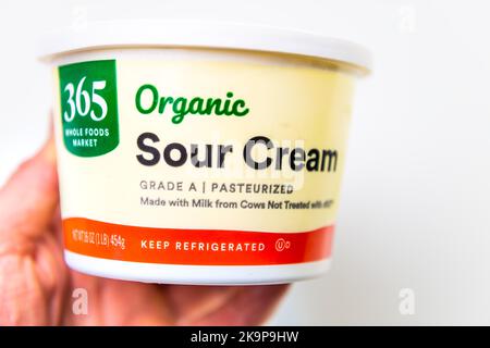 Naples, USA - October 21, 2021: Closeup macro of hand holding Whole Foods market 365 brand private label product, organic healthy sour cream Stock Photo