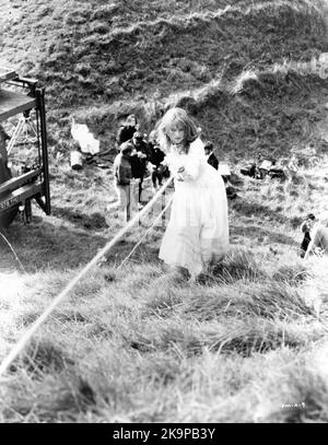 JULIE CHRISTIE in costume as Bathsheba Everdene uses a rope to climb up the steep slope of the grass ditch at ancient Maiden Castle, Dorchester, Dorset on set location candid with Film Crew during making of FAR FROM THE MADDING CROWD 1967 director JOHN SCHLESINGER novel Thomas Hardy screenplay Frederic Raphael Vic Films Productions / Metro Goldwyn Mayer Stock Photo