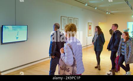 Tourists and locals enjoy the galleries at the goma or. Glasgow museum of modern art a video exhibit is viewed Stock Photo