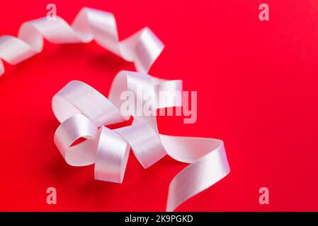 White ribbon with bow on a red background Stock Photo