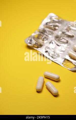 white capsules and pill pack on yellow background Stock Photo