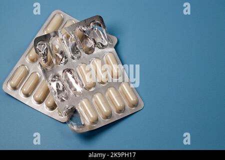 white capsules and pill pack on blue background Stock Photo