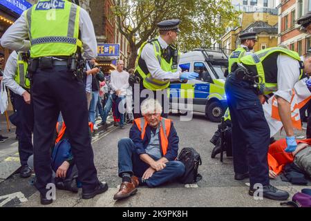 London, UK. 29th October 2022. Police officers arrest a protester. Just Stop Oil activists blocked Charing Cross Road near Leicester Square as they continue their protests demanding the government stops issuing new fossil fuel licences. Credit: Vuk Valcic/Alamy Live News Stock Photo