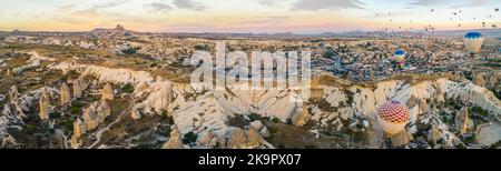 Panoramic view of hot air balloons flying high in the sky over Cappadocia breathtaking landscape, the city and fairy chimneys valley in Turkey. High quality photo Stock Photo