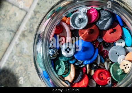 assortment random colored loose buttons in a glass jar Stock Photo