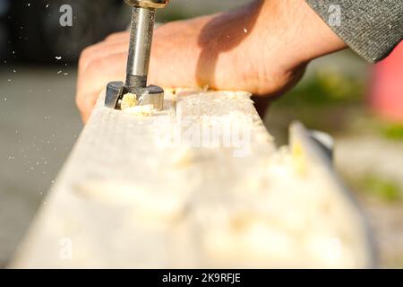 Drilling a hole in a wooden beam with a drill. Stock Photo