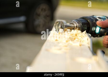 Drilling a hole in a wooden beam with a drill. Stock Photo