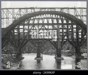 The railway bridge over the Öre River during construction, with workers on the bridge. Stock Photo