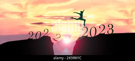 2023 Happy New Year concept, Young woman Jumping across the gap of the mountain from Old year 2022 to 2023 New Year.