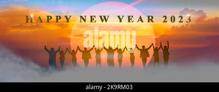 Happy new year 2023, Keep fighting together, Silhouette of 2023 letters on the mountain with business people raised arms in teamwork concept at sunris Stock Photo