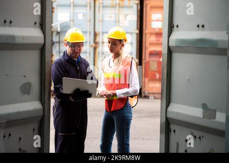 Young worker team with laptop at container terminal port warehouse for check stock product. Stock Photo