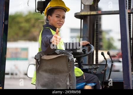 Female worker driving forklift in industrial container warehouse. Stock Photo