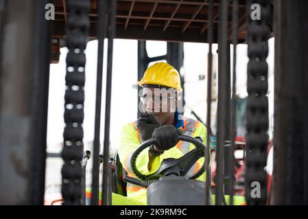 Worker man driving forklift in industrial container warehouse. Stock Photo