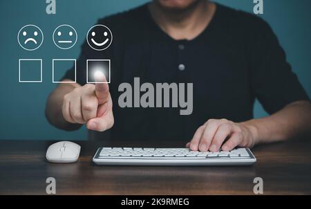 Customer service and satisfaction concept ,Business people using computer and touching the virtual screen on the happy Smiley face icon to give satisf Stock Photo