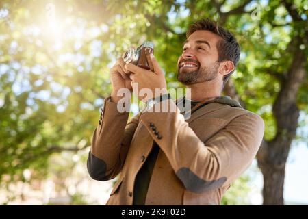 Hes a photographer at heart. a handsome young man taking photographs during his morning commute. Stock Photo