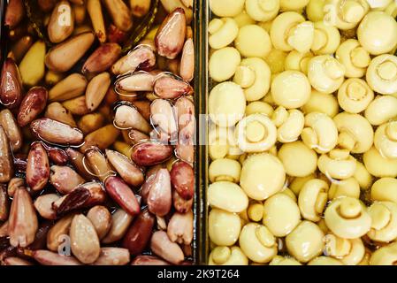 Theres two sides to a story. mushrooms and pine nuts displayed next to each other at a market during the day. Stock Photo