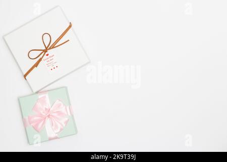 Christmas concept, Green pastel gift box wraps pink satin ribbon and white gift box with card. Stock Photo
