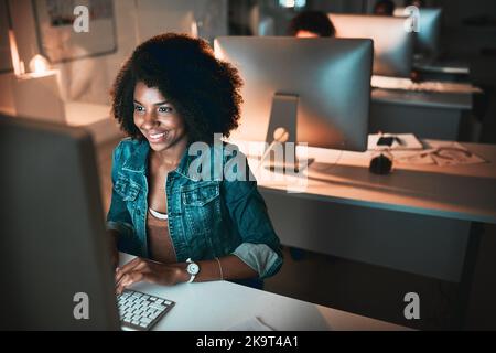 She has no problem working late. High angle shot of an attractive young female designer working on her computer in the office. Stock Photo