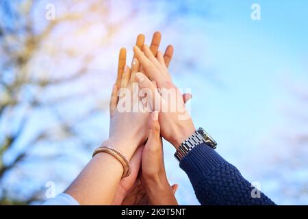 Were in this together. university students standing outside with their hands together. Stock Photo