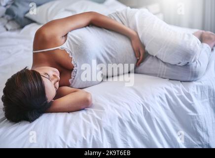 Pregnancy really takes a toll on your energy levels. a pregnant woman lying on her bed.