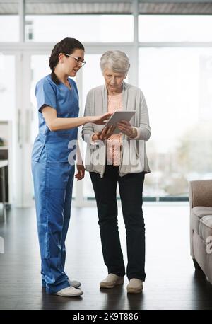 All your results at the touch of a button. Full length shot of a young female nurse showing her senior female patient something on a digital tablet. Stock Photo