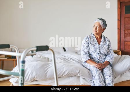Today starts the rest of my life. a confident mature woman looking outside trough her window while contemplating at home during the day. Stock Photo