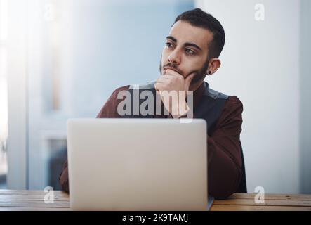 Every entrepreneur needs to constantly be thinking of new ideas. a young businessman looking thoughtful while working on a laptop in an office. Stock Photo