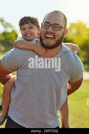 Ill do anything to make her happy. an adorable little girl and her father enjoying a piggyback ride in the park. Stock Photo