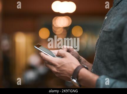 Lets invite some people. an unrecognizable man browsing on a cellphone while standing inside of a beer brewery during the day. Stock Photo