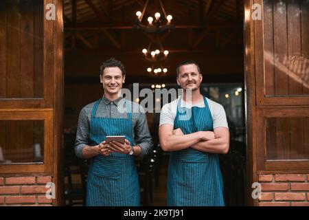 This is where our dreams come true. Portrait of two cheerful young businessmen standing together casually in front of a beer brewery outside during Stock Photo