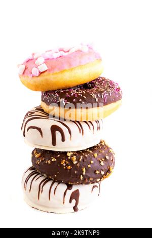 Fresh donuts with different frosted, chocolate, pink glazed and sprinkles on white background with copy space. Assortment of various colourful donuts. Stock Photo