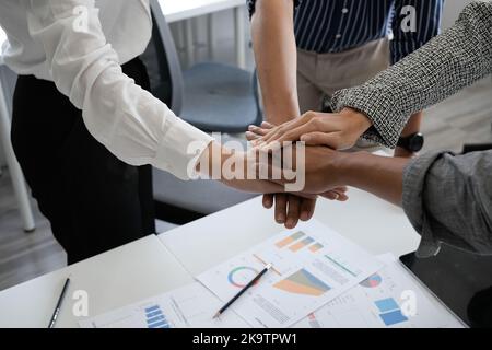 Close up happy diverse business people putting hands together, showing support and unity. Multiracial colleagues involved in team building activity Stock Photo