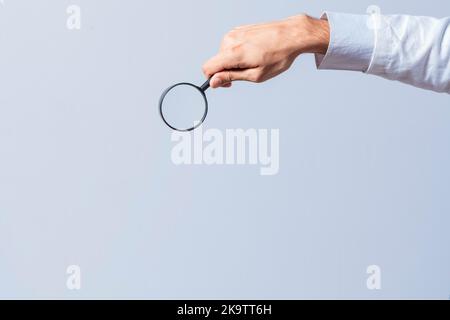 Hand holding magnifying glass on isolated background. Man's hand holding magnifying glass on white background. Hand holding magnifying glass looking Stock Photo