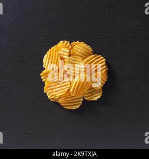 Potato chips on a black stone background, top view Stock Photo