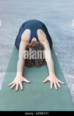 Young hispanic woman doing yoga on the green open mat at outdoor. Concept for fitness o yoga. Copy space. Stock Photo