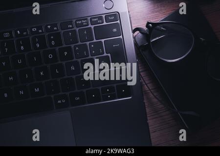Top view of wood vintage desk focused on laptop with notepad, and glasses. Workplace. Work from home. Office desk. Stock Photo