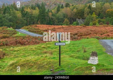 Elterwater in the English Lake District, signpost to the village with vibrant orange and gold colours of Autumn.  Copy space.  Horizontal. Stock Photo