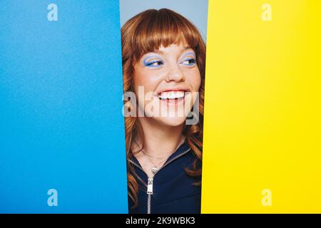 Red haired woman standing behind two geometric shapes. Happy woman having fun in an art and design studio. Stock Photo