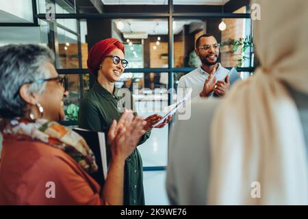 Successful businesspeople applauding cheerfully during a staff meeting in a modern office. Group of multicultural entrepreneurs running a startup in a Stock Photo