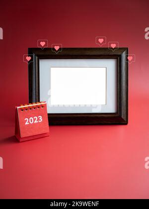 Template for photo frame for card and small 2023 year red desk calendar and love like heart icons on red background, minimalist. Empty white blank spa Stock Photo