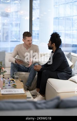 Two multiracial businessmen discuss on-line presentation on tablet Stock Photo